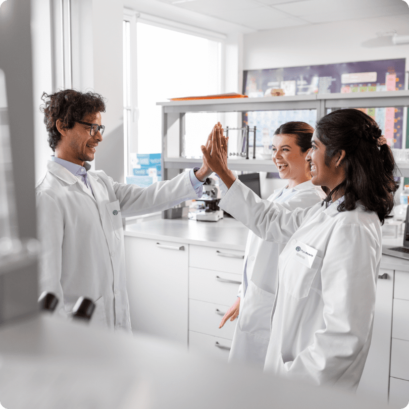 Three scientists in white coats work in a PhytoSerenity laboratory, analyzing samples and discussing the results.